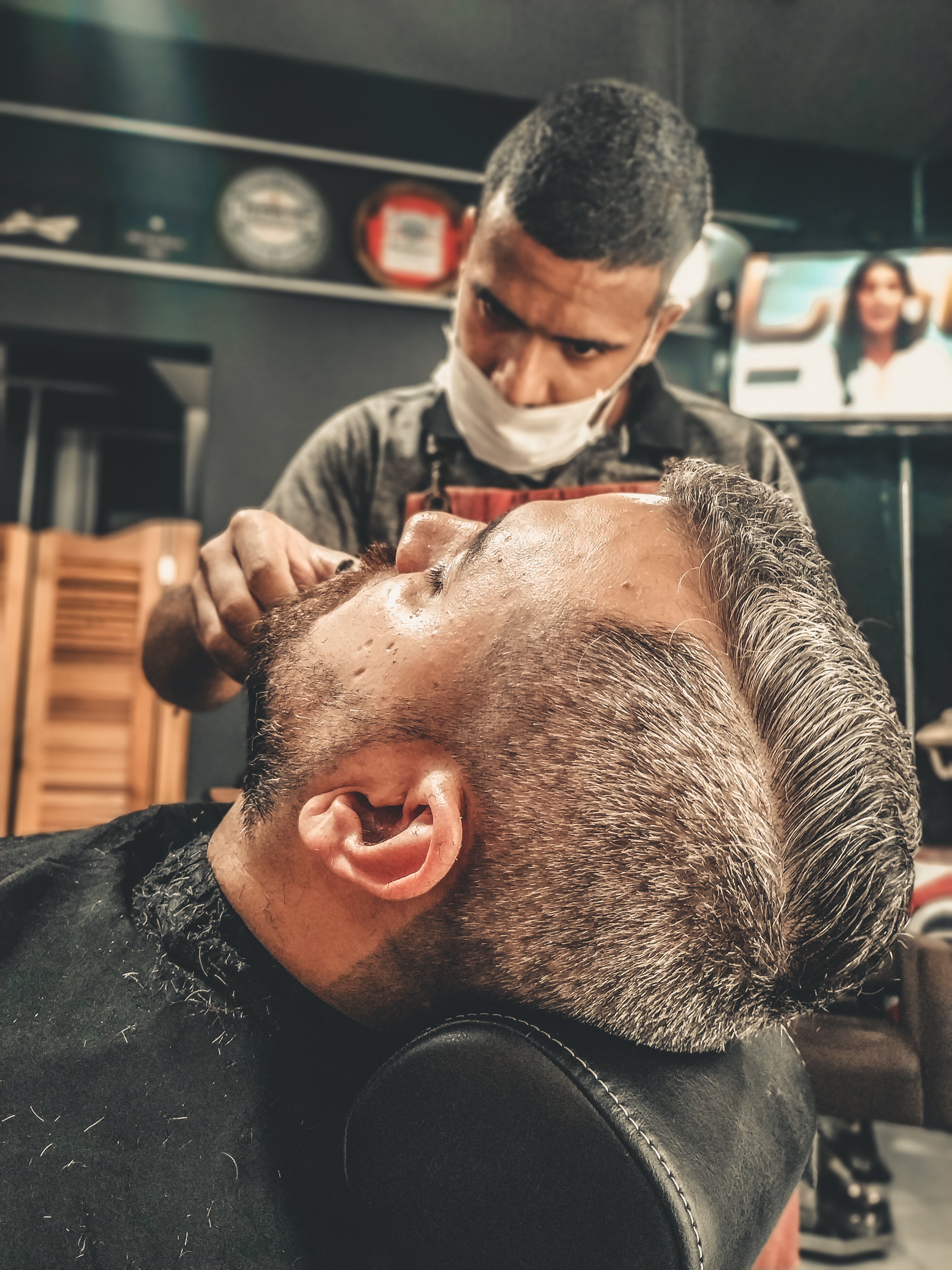 Barbeiro fazendo a barba de um cliente.